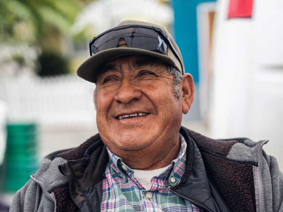 Smiling farmer in a cap and plaid shirt behind crates of berries